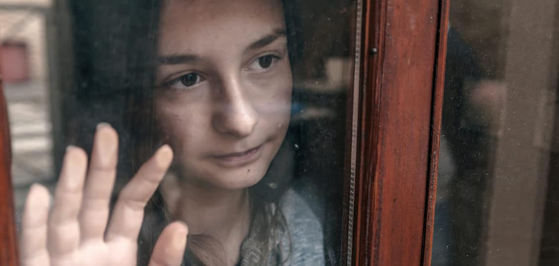 Sad teenage girl looking out the window on a cold autumn day, alone thoughtful sadness girl is sad at the window, Emotional portrait of a teenage girl looking troubled. autumn depression