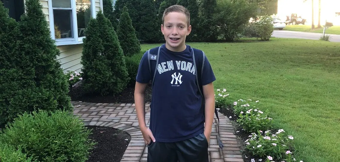 Young teen boy on the first day of school posing in front of house first day of 2020 school year