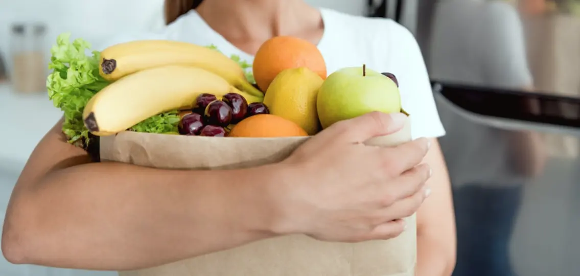 a teen girl holding a bag of groceries full of fruit and vegetables, orthorexia concept