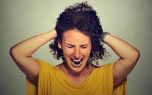 Stress. Woman stressed is going crazy pulling her hair in frustration isolated on gray wall background. Negative human emotions feelings reaction