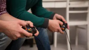 Close up view of men holding joysticks to video console. Modern concept of popular video games .