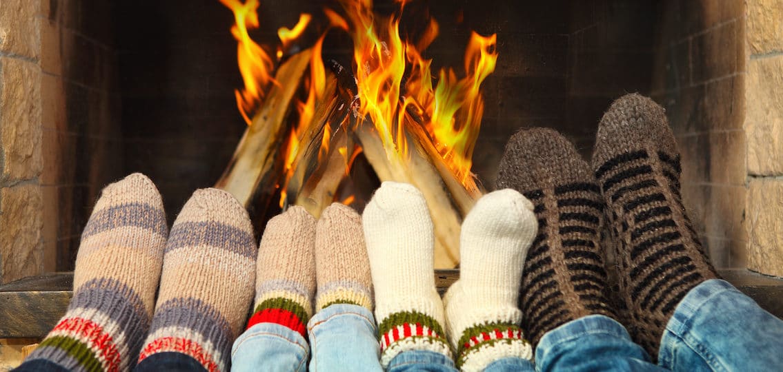 Feets of a family wearing woolen socks warming near the fireplace