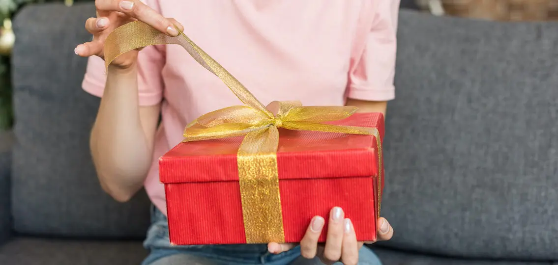 teen girl opening a gift on a couch close up