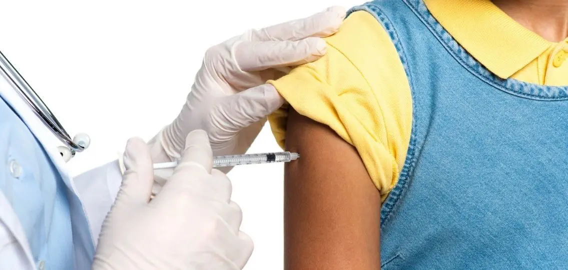 teenager getting a vaccine shot in her arm from doctor close up
