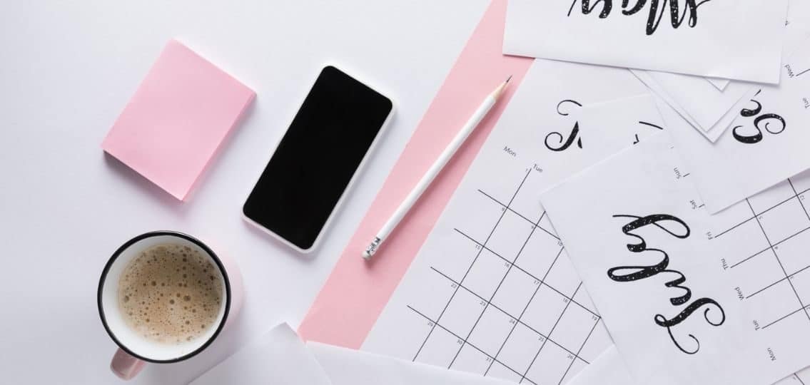 custody schedule calendars scattered on a white desk with coffee, post-it notes, and a phone