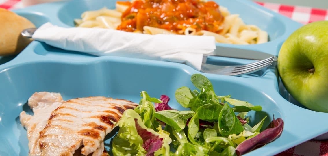 a healthy tray of food at a school cafeteria with pasta chicken and salad