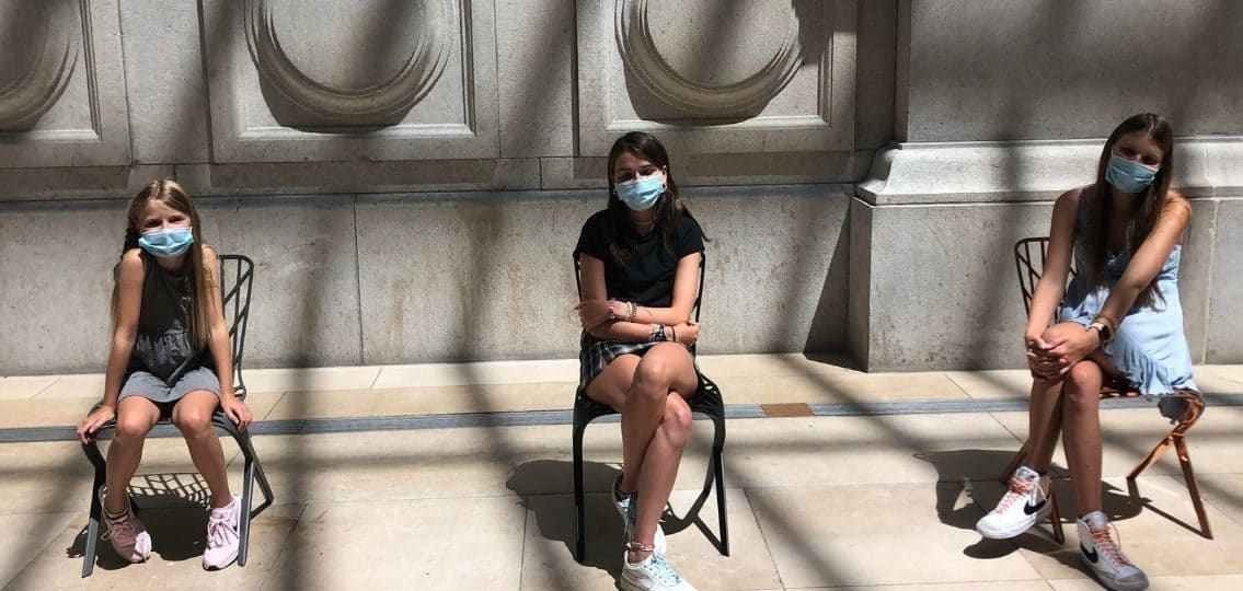 Author Catherine Brown's teen daughters sitting in chairs wearing masks