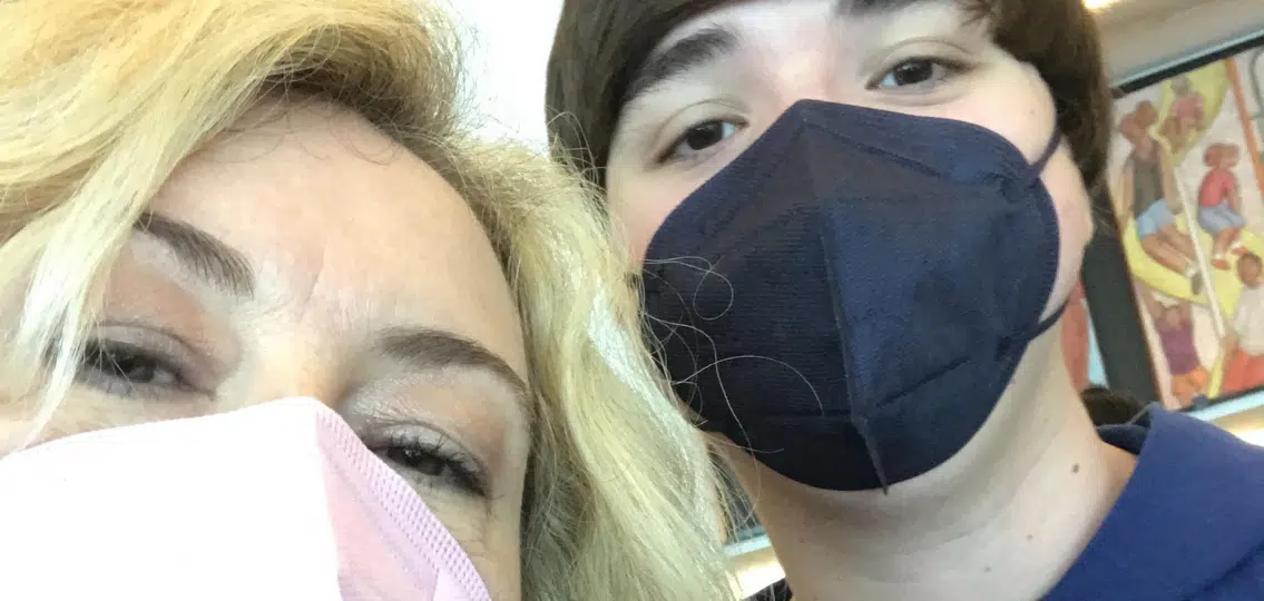 author with son on a road trip together taking a close up selfie both wearing masks
