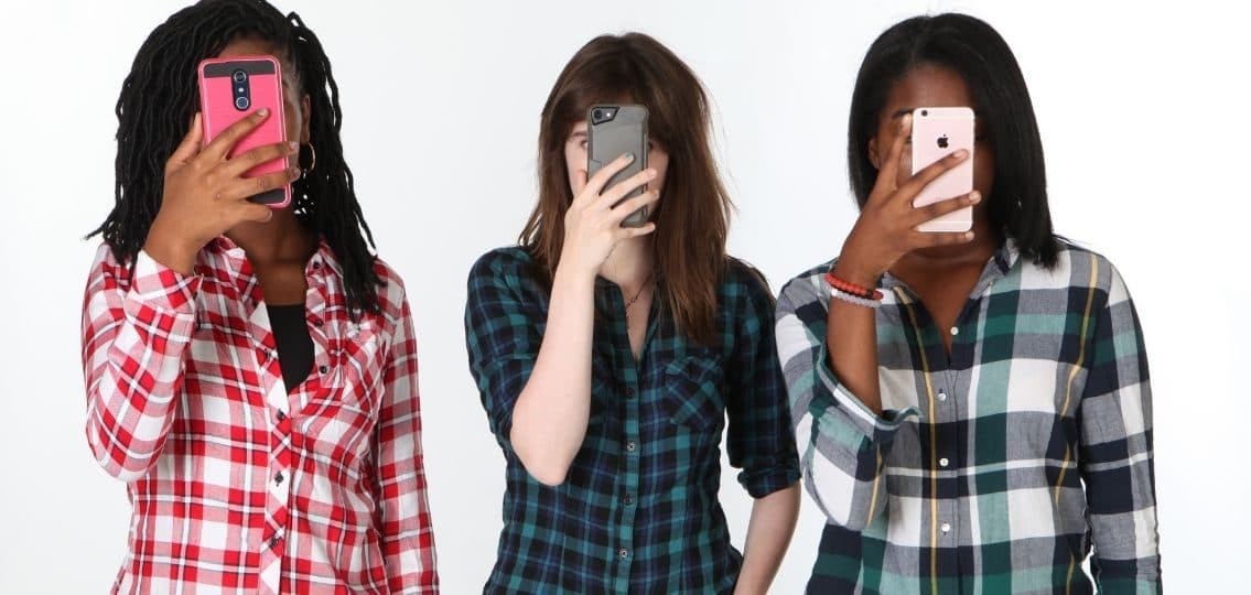 teen girls being consumed by social media with phones covering their faces