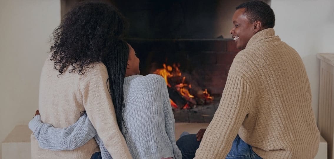 a family connecting with their teen in front of a fireplace at night