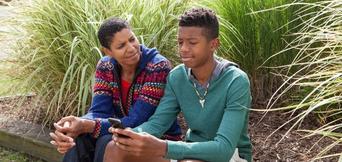 um adolescente ignorando sua mãe no telefone fora