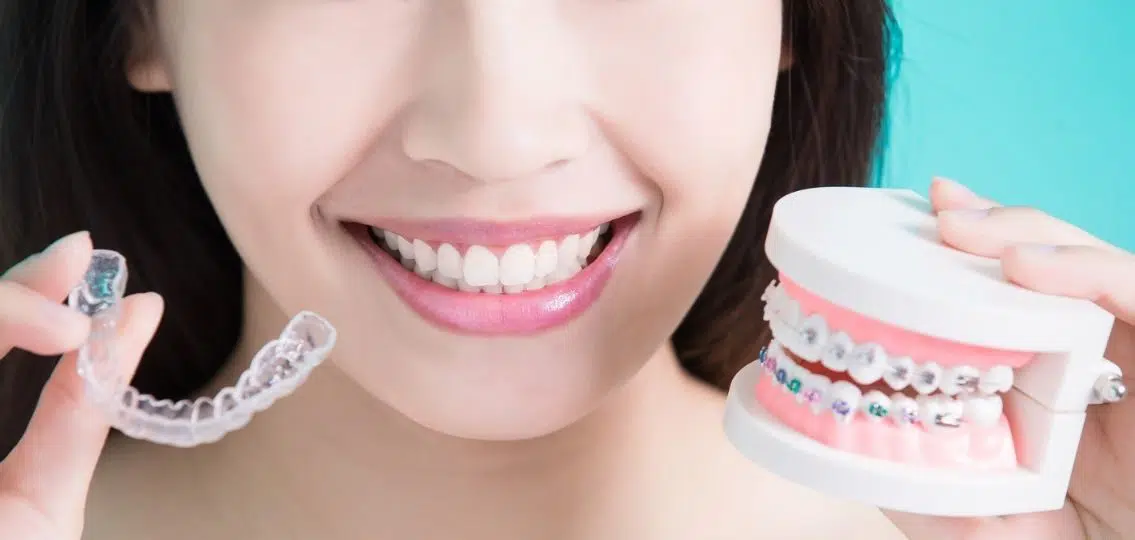 close up woman choosing between different types of braces, traditional braces vs Clear Tray Aligners