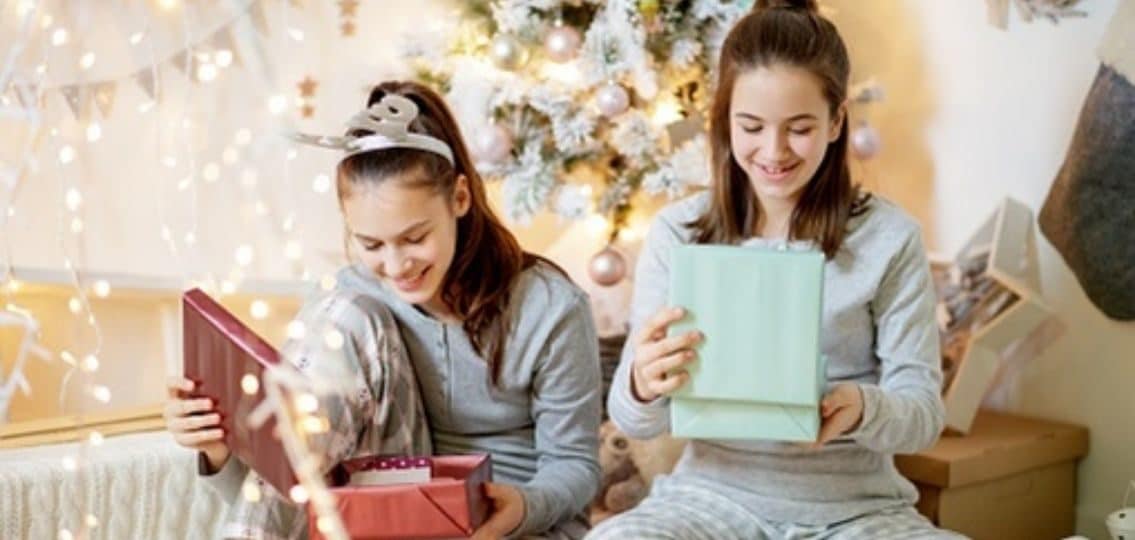 teen girls opening their gifts on christmas and smiling
