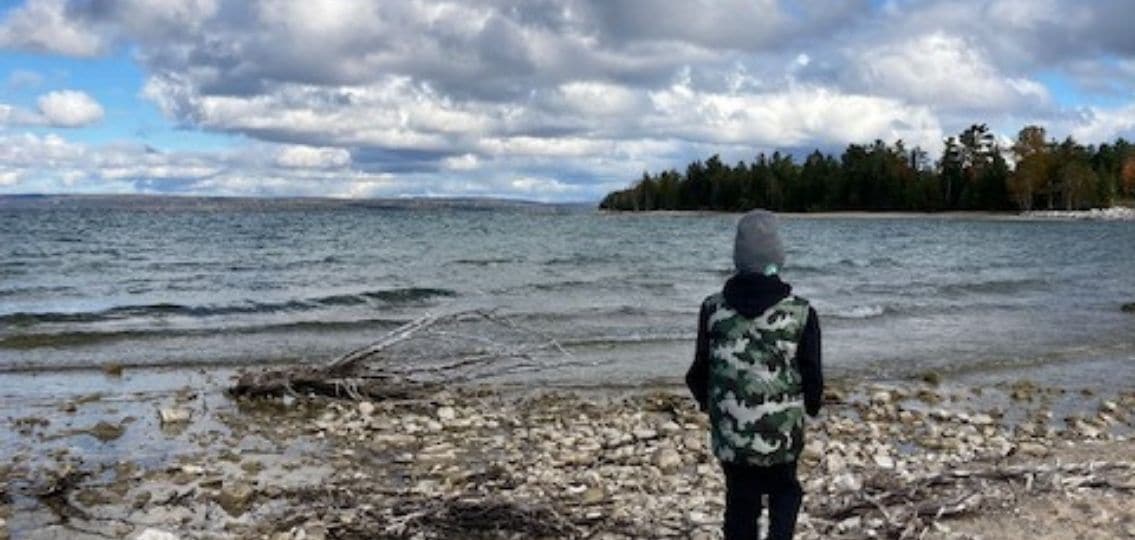 a teen outside on a hike in front of a large body of water