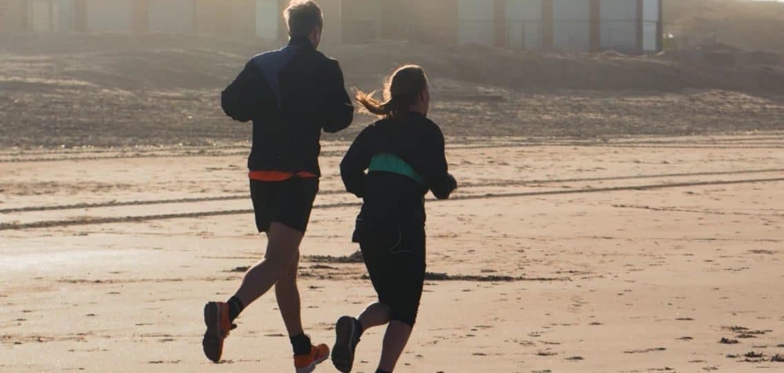 a man and woman taking own advice jogging on the beach away from camera