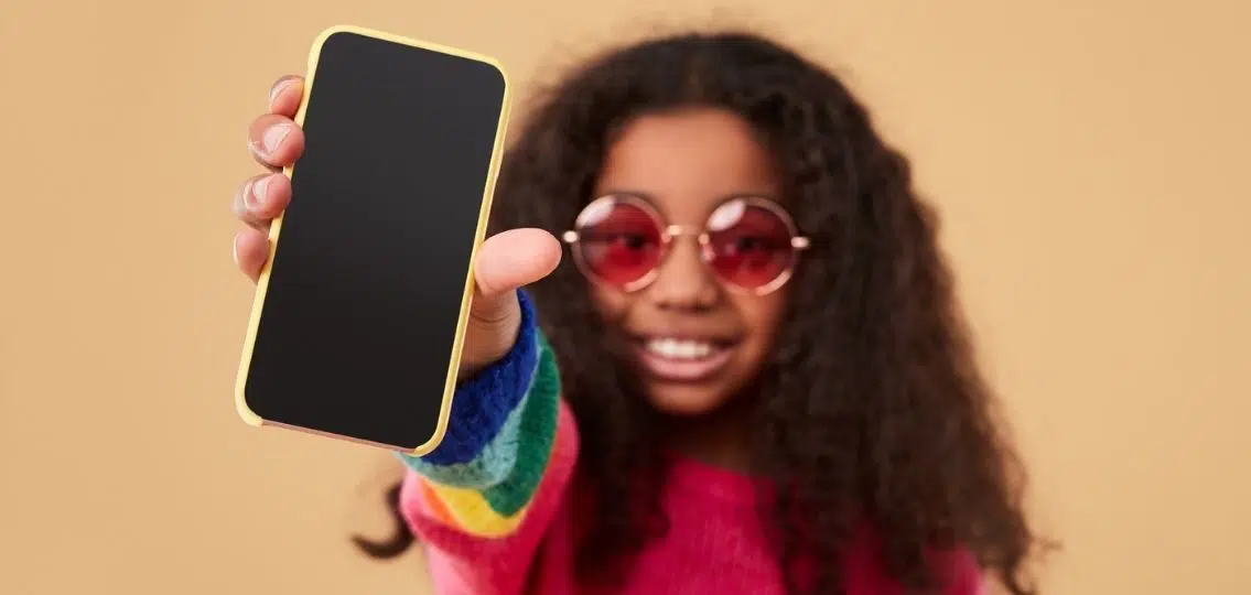 a tween with a family cell phone contract holding up a smartphone