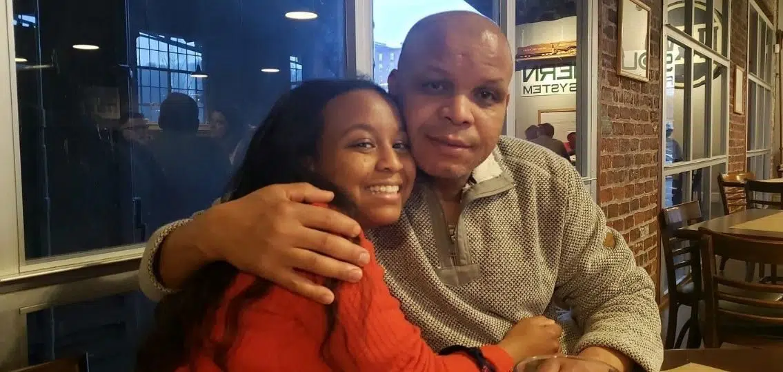 Black family author with her father hugging at a restaurant