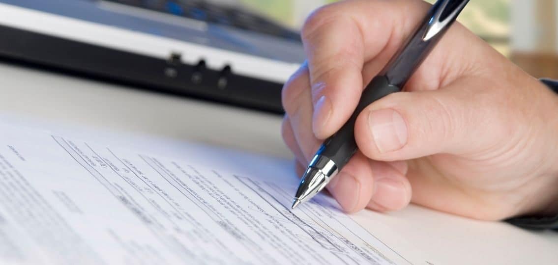 a close up of a teenager signing legal documents for basic estate planning