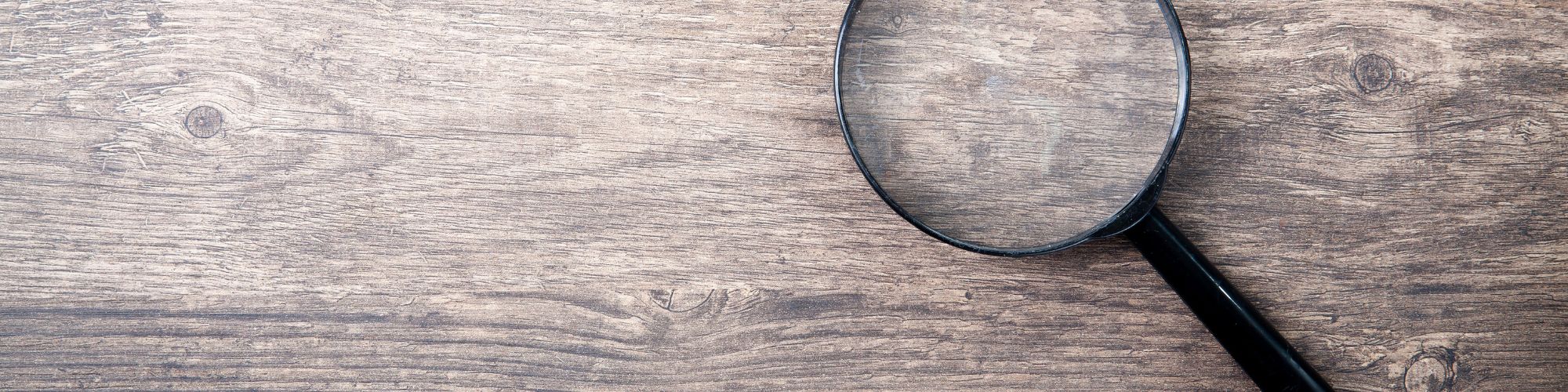 close up of a magnifying glass on a wooden background