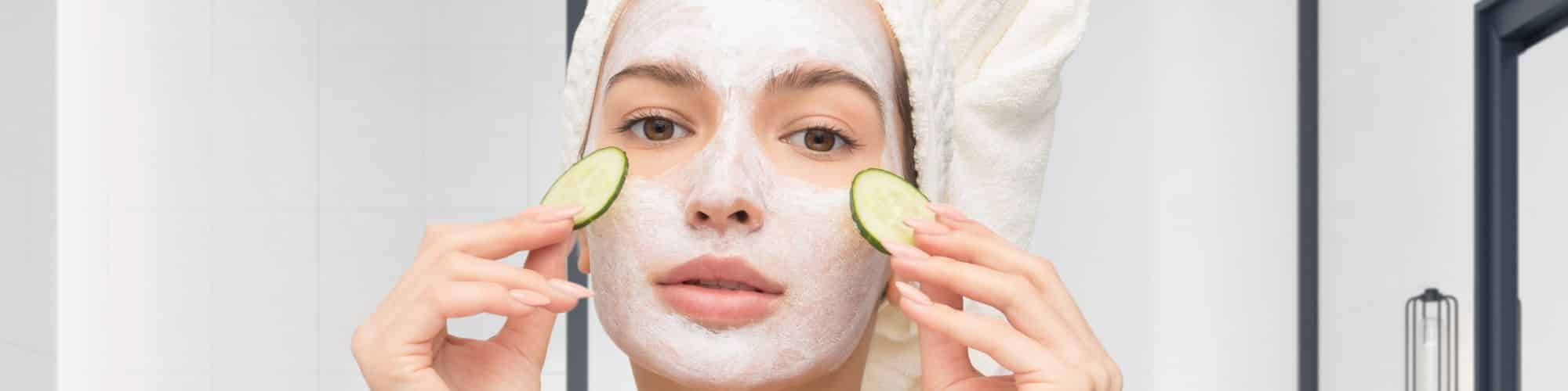 A teenager in a spa robe with a face mask taking cucumbers from her eyes