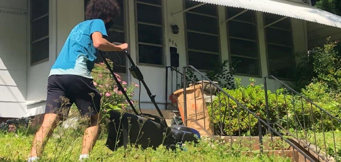 a teen boy mowing his neighbor's overgrown lawn