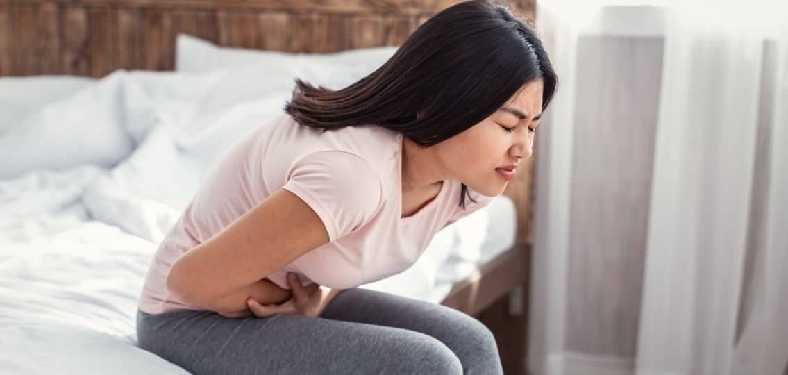 A teenage girl doubled over in pain due to painful period cramps