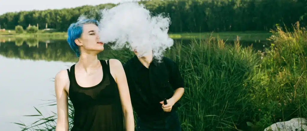 Two teenagers vaping outside and damaging their dental health and teeth