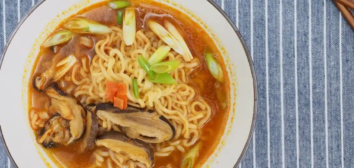 A close up of delicious instant ramen with toppings like mushrooms and green onion