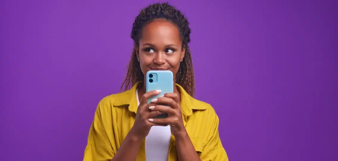 A teen girl smiling with her phone in front of her face trying out a teen dating app