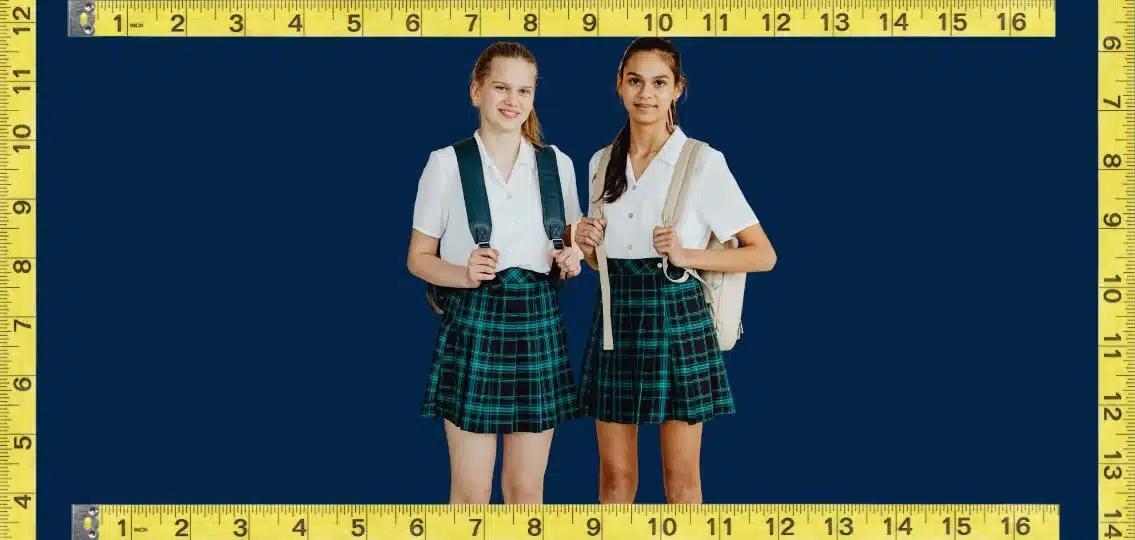 Two teen girls in a school uniform surrounded by measuring tape