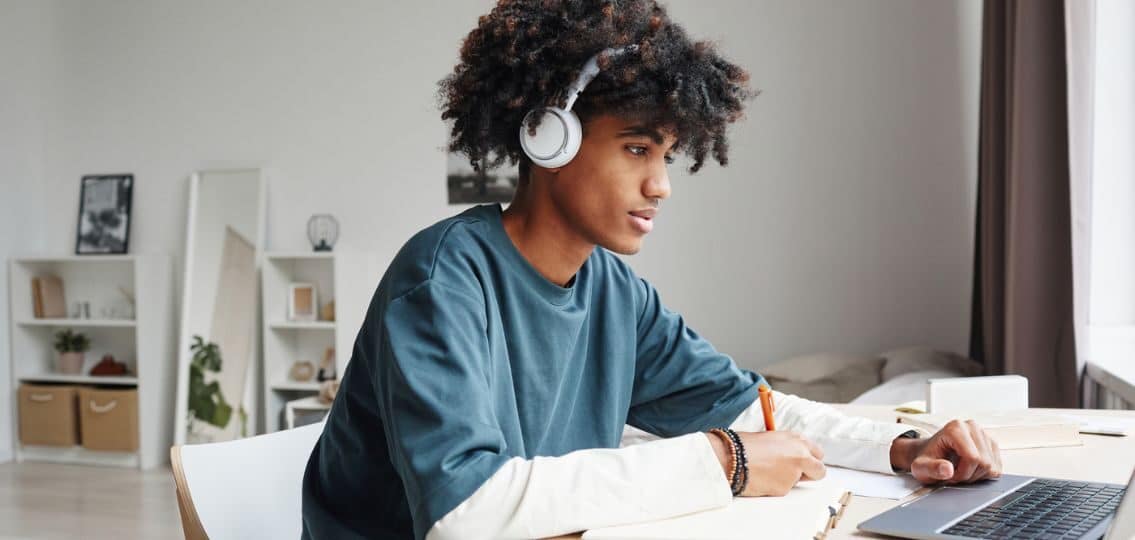 a college student with adhd doing his homework with headphones on