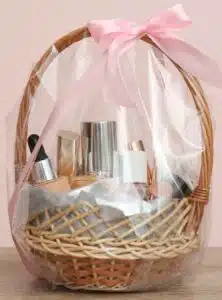 basket with makeup bottles wrapped in plastic and a pink bow