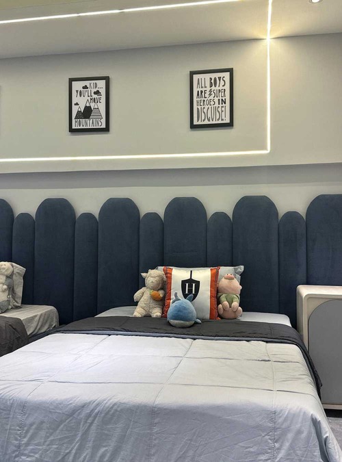 bed with white linens and a blue headboard against a white wall