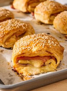 baking pan with puff pastry wraps filled with ham and cheese