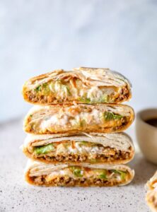 four wraps with ground turkey, cheese, and lettuce stacked on a plate