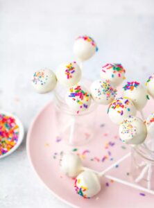 cake pops with white icing and covered in sprinkles