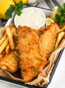 fried fish and french fries in a basket with a bowl of tartar sauce