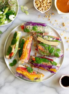 a plate of spring rolls made with lettuce, tofu, carrots, bell peppers, and purple cabbage