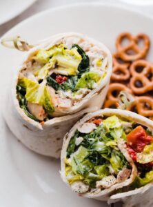 2 chicken caesar wraps on a plate with pretzels