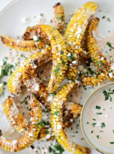 seasoned air fryer corn ribs on a plate with dipping sauce
