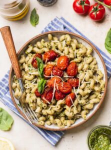 bowl of pesto pasta with cherry tomatoes on top
