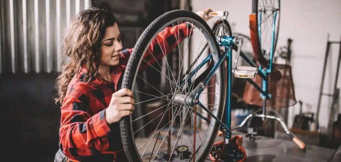 teen girl working on a bicycle that's upside down on a table