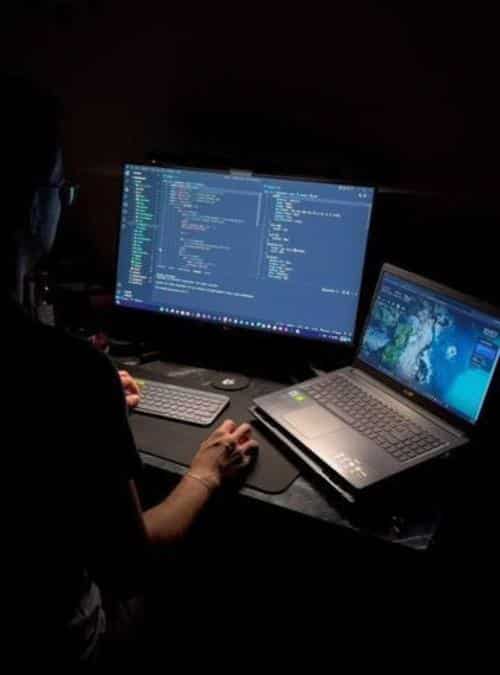 a person using a laptop and a keyboard and monitor