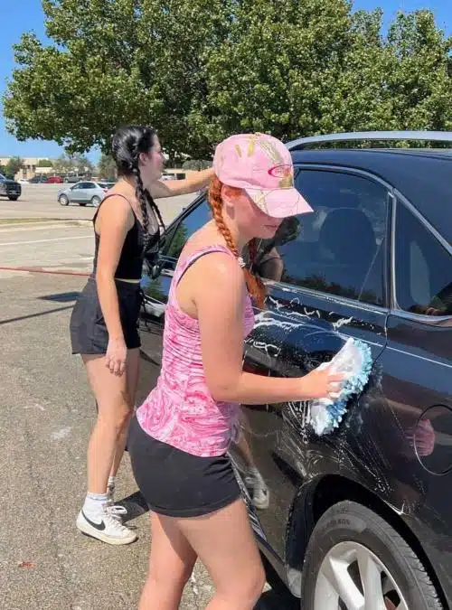 two teen girls washing a car