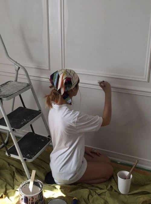 woman sitting on the floor painting a wall