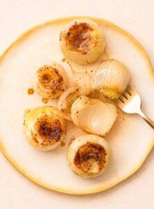 cooked whole onions with seasoning on a plate