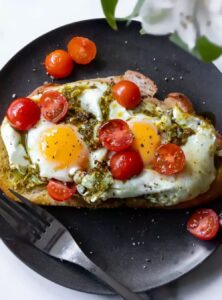 fried eggs on toast with pesto and cherry tomatoes