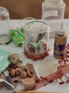 jars, acorns, glue, and other decorations used for making homemade snow globes