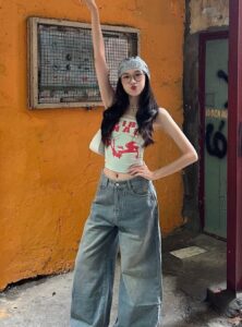 woman with long black hair wearing a tank top and wide-leg jeans