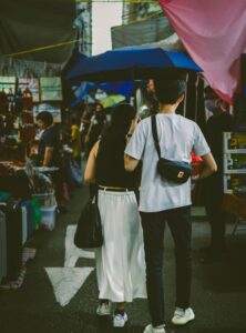 two people with an umbrella walking down a busy street